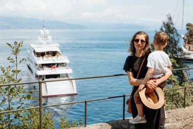 Oğlunu kucağında tutan anne Portofino, İtalya 'da ligurian denizinde seyreden lüks bir yatın keyfini çıkarıyor.