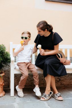 Anne ve oğlu bir bankta oturmuş, Portofino, İtalya 'nın büyüleyici köyünde dondurmanın ve birlikteliğin tadını çıkarıyorlar.