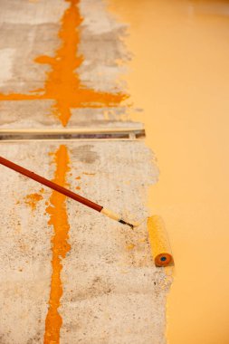 İnşaat işçisi beton zemine epoksi reçine sürüyor.