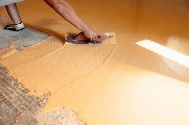 İnşaat işçisi epoksi reçinenin yüzeyini bir malayla düzleştiriyor.