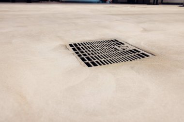 Endüstriyel bir binada yeni dökülmüş bir epoksi zemininde drenaj.