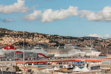 Büyük yolcu gemileri güneşli bir günde arkalarında şehir manzarasının yükseldiği Genova, İtalya limanına demirlemiştir.
