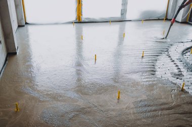 İnşaatçılar beton bir pompa kullanarak zemine beton karışımı dökerek pürüzsüz bir yüzey oluşturuyorlar.