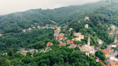 İtalyan Rivierası 'nın büyüleyici bir köyü olan Camogli' nin havadan görünüşü bulutlu bir gökyüzünün altında yemyeşil renkli evler sergiliyor.