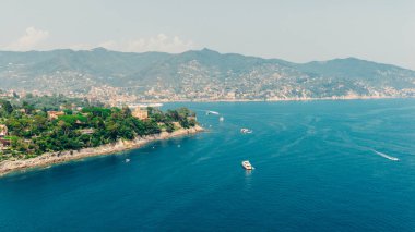 İtalya 'nın liguria şehrinde bulunan ve yemyeşil bitki örtüsü ve dağlarla çevrili güzel bir kasaba olan Camogli' nin güzel kıyı şeridinde yelken açan teknelerin hava manzarası.