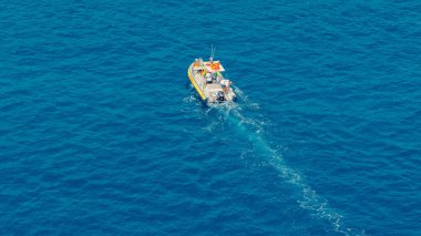 Liguria, İtalya 'da Camogli yakınlarında açık mavi bir denizde yelken açan beyaz ve sarı bir tekne.