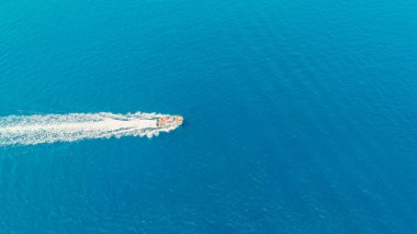 Camogli, Liguria, İtalya yakınlarında mavi sularda yüzen bir motorlu teknenin havadan görünüşü beyaz bir iz bırakıyor.