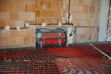 İnşaat alanına zemin altı ısıtma sistemi için kırmızı ve siyah plastik borular kuruluyor