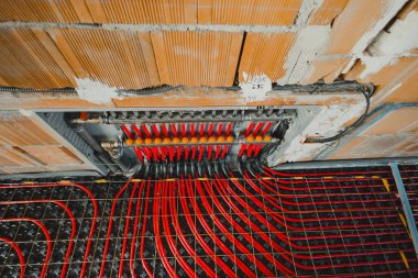 Yeraltı ısıtma sisteminin kırmızı ve siyah plastik boruları yeni bir binanın metal ağlarına monte ediliyor