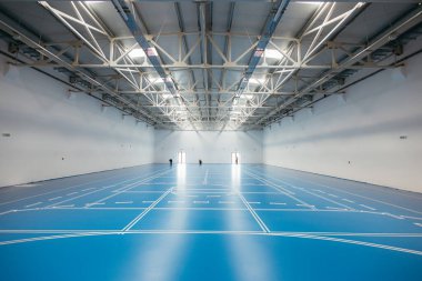 İşçiler, endüstriyel kullanım için alanı hazırlayan büyük, modern bir depoda mavi bir epoksi tabana bant yapıştırıyorlar.