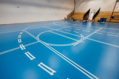 Beyaz işaretleme bandı spor salonundaki mavi epoksi tabana uygulanacak.