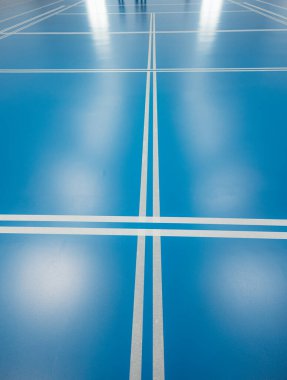 Boş badminton kortu mavi epoksi reçine zemin ve oyun alanını gösteren beyaz çizgiler