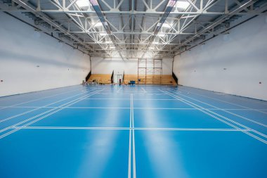 İşçiler büyük bir spor salonuna epoksi taban döşemesi kurmayı bitiriyorlar