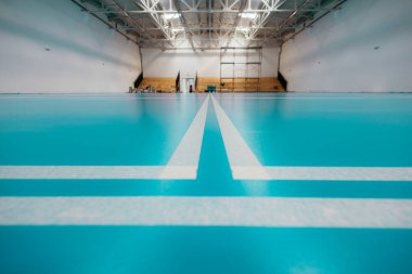 Yenileme sırasında spor salonunda yepyeni bir epoksi zemin üzerinde oyun alanını gösteren beyaz çizgiler.