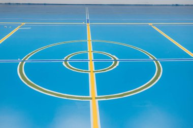 İşçiler spor salonuna epoksi reçine döşeme uyguluyorlar, çeşitli spor dalları için renkli çizgiler ve daireler çiziyorlar.