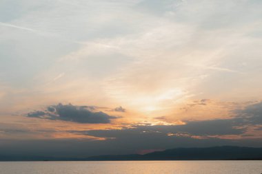 Sakin bir gölün üzerinde güzel bir günbatımı. Arkasında dağlar var. Huzurlu ve huzurlu bir atmosfer yaratıyor.