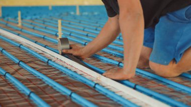 Tesisatçı kurulum sırasında alt kattaki ısıtma borularına izolasyon sağlıyor.