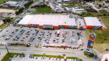 Geniş bir park yeri ve çatıda modern pvc membranlı hvac sistemi olan büyük bir ev geliştirme mağazasının havadan görüntüsü.