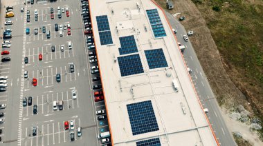 Güneş panelleri olan ticari bir binanın çatısı yeşil enerji ve arabalarla dolu bir otopark.