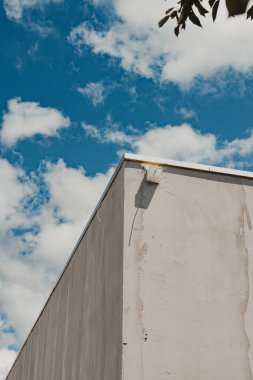 İnşaat halindeki gri beton duvar elektrik kutusu ve kabloyla bulutlu mavi gökyüzüne karşı