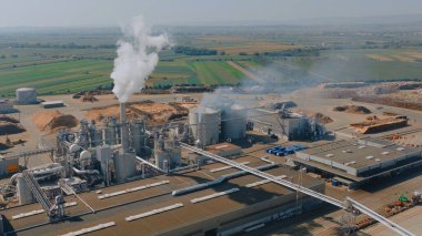 Kereste işleme tesisinin hava görüntüsü duman ve buhar yayıyor, endüstriyel aktiviteleri ve çevresel etkileri vurguluyor