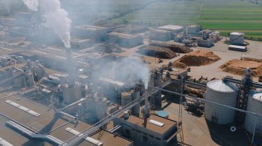 Bir kereste fabrikasının hava görüntüsü duman ve buhar yayıyor, çevresel etkileri ve endüstriyel süreçleri vurguluyor