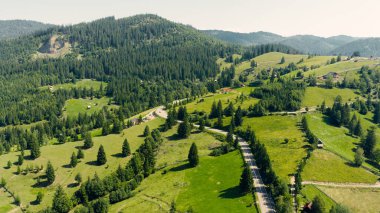Yemyeşil vadiler ve tepeler boyunca kıvrılan dolambaçlı bir yolun nefes kesici hava manzarası pitoresk bir manzara yaratıyor.