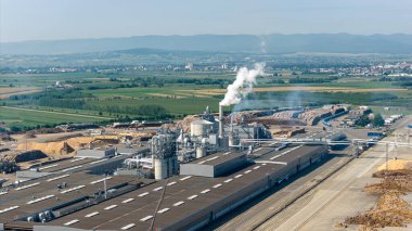 Duman yayan, çevresel etkiyi ve endüstriyel aktiviteyi vurgulayan bir ahşap işleme fabrikasının hava görüntüsü