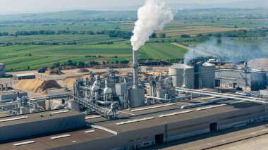 Duman ve buhar yayan, yenilenebilir enerji üretimi ve çevresel etkiyi vurgulayan bir biyokütle enerji santralinin hava görüntüsü