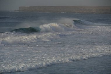Okyanus kıyısında dalgalar kopuyor.