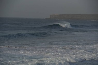 İsrail 'in kuzeyindeki Akdeniz kıyısında okyanus dalgaları. Arka plan eski bir taş yapıdır. İsrail için bir yer.