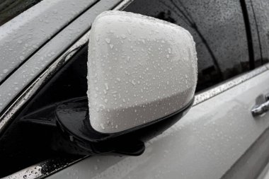 Beyaz araba yan dikiz aynasında yağmur damlaları