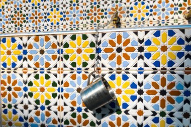 Etrafında mozaik fayanslar olan bronz su musluğu.