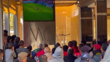 İnsanlar Fas 'ta bir kafede oturup televizyonda futbol izliyorlar. 