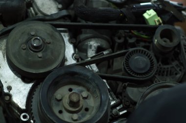 Tamir edilen eski bir motor, eski gri bir arabaya yerleştirilmeden önce besleniyor.