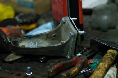 Tamir edilen eski bir motor, eski gri bir arabaya yerleştirilmeden önce besleniyor.