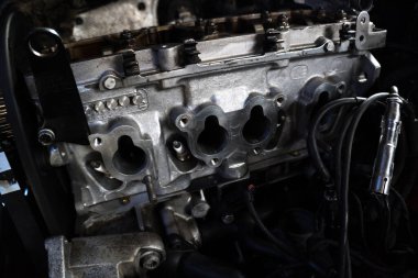 Tamir edilen eski bir motor, eski gri bir arabaya yerleştirilmeden önce besleniyor.