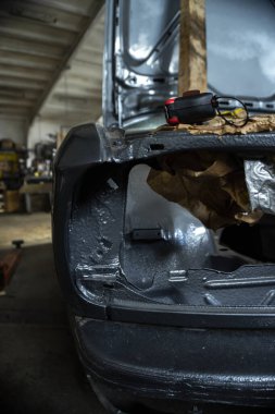 Asansördeki bir kutuda restore edilen eski gri bir araba.