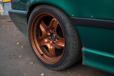 Sonbaharda metalik yanmış turuncu jantlar üzerinde akort edilmiş yeşil araba