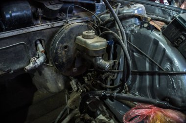 Tamir edilen eski bir motor, eski gri bir arabaya yerleştirilmeden önce besleniyor.