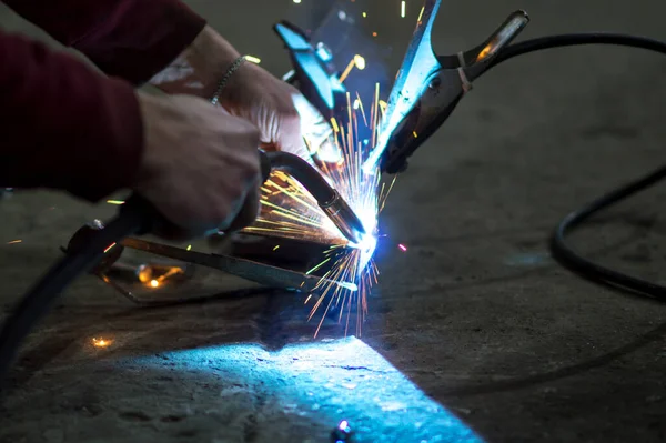 welder in the dark performs welding work on the metal with a welding machine