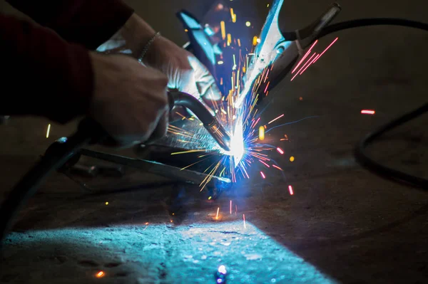 welder in the dark performs welding work on the metal with a welding machine