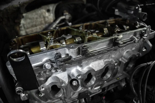 Stock image n old engine under repair is being fed before installation in an old gray car