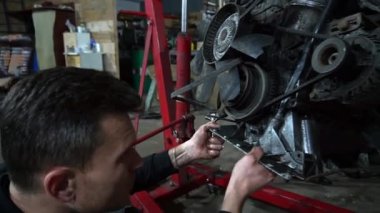 Bir tamirci tamir ve akort için kırmızı asansörde eski kirli bir araba motorunu söker.