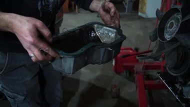 Bir tamirci tamir ve akort için kırmızı asansörde eski kirli bir araba motorunu söker.