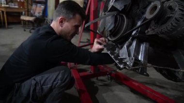Bir tamirci tamir ve akort için kırmızı asansörde eski kirli bir araba motorunu söker.