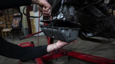 Bir tamirci tamir ve akort için kırmızı asansörde eski kirli bir araba motorunu söker.