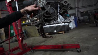 Bir tamirci tamir ve akort için kırmızı asansörde eski kirli bir araba motorunu söker.