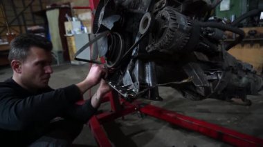 Bir tamirci tamir ve akort için kırmızı asansörde eski kirli bir araba motorunu söker.