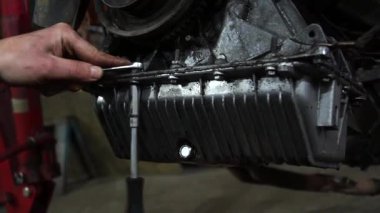 Bir tamirci tamir ve akort için kırmızı asansörde eski kirli bir araba motorunu söker.